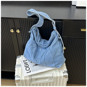 Detail van lichtblauwe denim draagtas met golfstiksels op een witte koffer