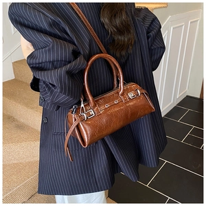 Détail macro du sac en cuir marron avec texture cirée brillante et boucle métallique