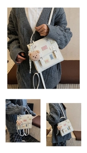 Detail of white crossbody bag with cute embroidery and brown plush bear keychain charm