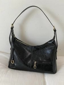 Glossy black oil wax leather tote bag with gold hardware shown in a front view