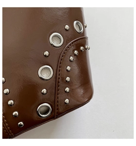 Gros plan d'un cabas en cuir marron foncé avec œillets métalliques et rivets argentés