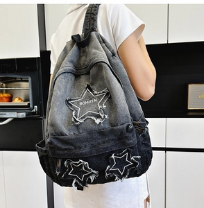 Detailed view of grey gradient denim backpack with star patchwork and frayed embroidery