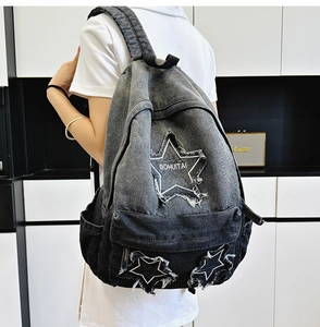 Detailed close-up of a gradient denim backpack with star patches and frayed edges