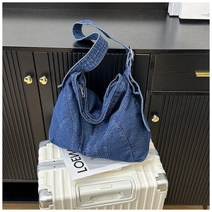 Detail van vintage gewassen denim tas met witte stiksels en zilveren rits op de koffer