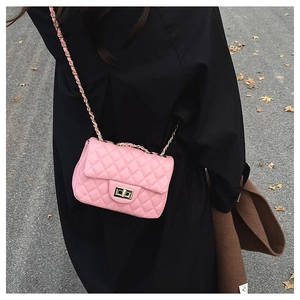 Detail einer rosa gesteppten Umhängetasche mit goldener Kette an einem Modell