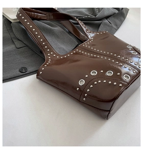 Détail du sac seau en cuir verni marron foncé avec des rivets métalliques argentés