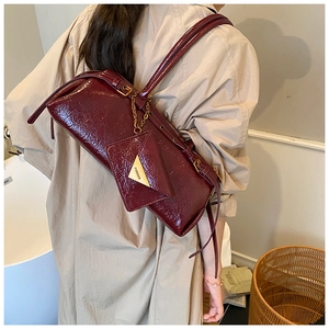 Détail du sac baguette en cuir verni bordeaux avec mini pochette et bandoulière