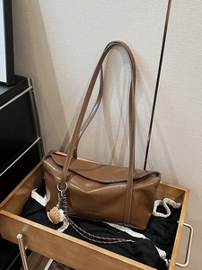 Brown gloss leather shoulder bag with long straps and charm in minimalist tote design