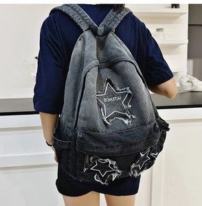 Detail view of denim backpack showing washed fabric and frayed star patchwork design