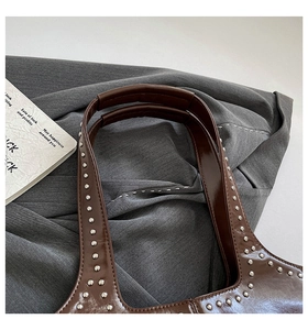 Détail de la poignée en cuir marron avec rivets argentés et surpiqûres de qualité