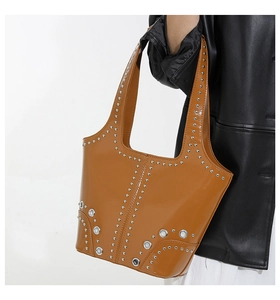 Détail du sac seau en cuir marron avec rivets argentés et large sangle intégrée