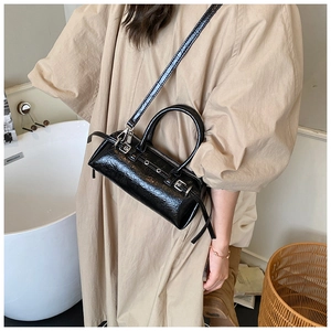 Détail du sac baguette noir brillant avec texture plissée et œillets métalliques