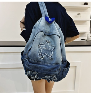 Detailed close-up of gradient denim backpack featuring frayed star-shaped patchwork
