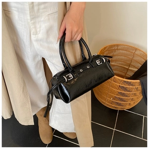 Détail du sac cylindre vintage en cuir verni noir avec boucles et œillets en métal argent