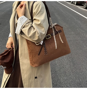 Détail du sac cabas en daim marron avec lanières en cuir et boucle dorée élégante