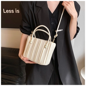 Détail de la texture plissée blanc crème et des ferrures dorées sur le sac à main