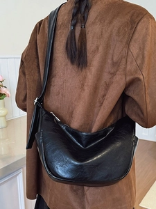 Minimalist black crescent crossbody bag with premium leather texture shown on model