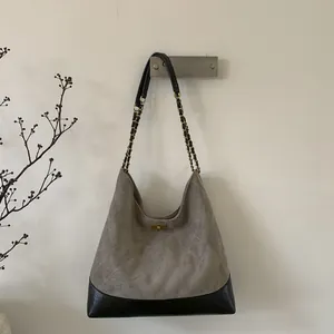 Detail of grey quilted suede tote bag with golden chain strap and metal turn-lock
