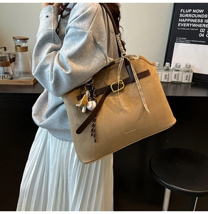 Détail du sac cabas en daim marron avec lanières en cuir et porte-clés de baseball