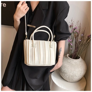 Détail du sac seau blanc cassé avec plis verticaux et accents de perles rondes
