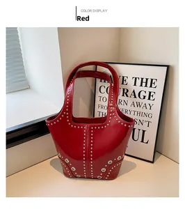 Détail du sac seau en cuir verni rouge avec rivets argentés et œillets métalliques brillants