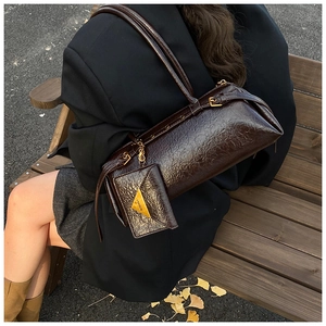 Détail du sac baguette en cuir marron foncé brillant avec un porte-monnaie à chaîne dorée