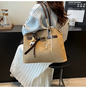 Détail du sac fourre-tout en daim kaki avec lanières en cuir marron et breloque baseball