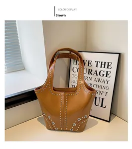 Détail du sac cabas marron avec rivets et œillets argentés sur fond minimaliste