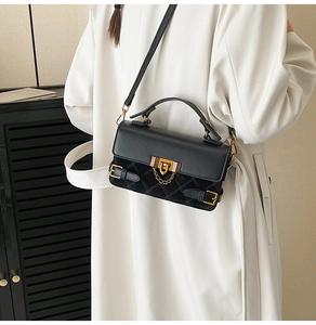 Close-up of black quilted shoulder bag featuring gold hardware and mixed textures