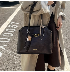 Détail du sac cabas noir vintage avec logo doré, foulard à carreaux et pendentif