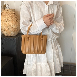 Détail du sac cabas plissé marron avec boucle décorative ronde et texture en cuir souple