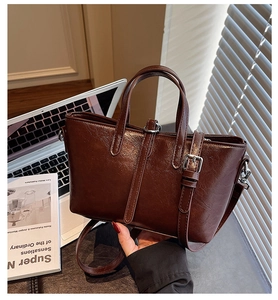 Detail view of dark brown faux leather bag with vintage texture and silver buckle