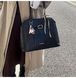 Détail du sac cabas noir avec boucle dorée, foulard en soie et pendentif de baseball