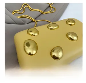 Dettaglio della borsa rigida gialla con grandi accenti in metallo dorato e catena
