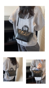 Detail of black trapezoid handbag with dual handles and silver metallic hardware
