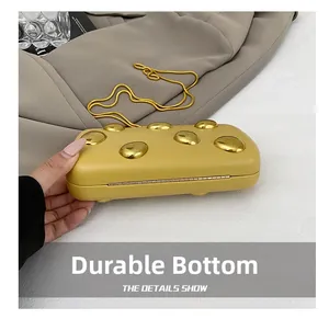Dettaglio della pochette in pelle zenzero con borchie dorate sulla base resistente all'usura
