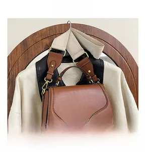 Détail du sac besace en cuir marron avec boucle dorée et large bandoulière en tissu