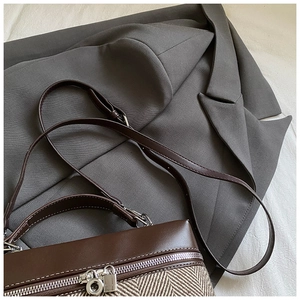 Detail view of contrast stitching handbag featuring herringbone fabric and silver hardware
