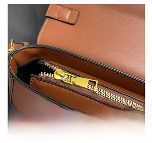 Détail macro de la fermeture éclair dorée et du cuir marron sur le sac bandoulière