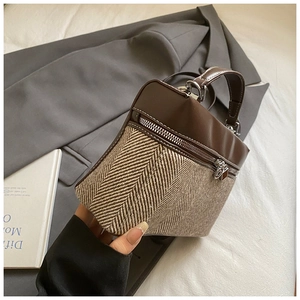 Detail of color-block bucket bag with brown leather, textured fabric, and silver hardware