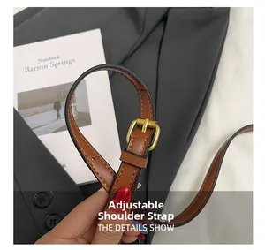 Détail de la bandoulière réglable en similicuir marron avec boucle dorée sur un sac