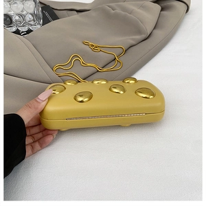 Dettaglio della borsa da sera in pelle giallo zenzero con decorazioni in metallo dorato