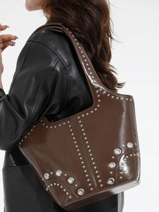Sac fourre-tout en cuir marron brillant avec rivets argentés porté par le mannequin