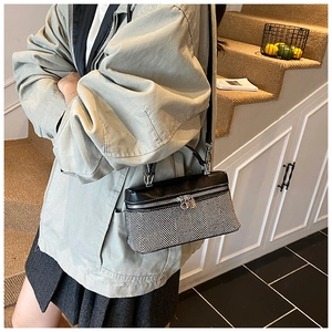 Detail of herringbone weave crossbody bag with silver hardware and leather flap on model
