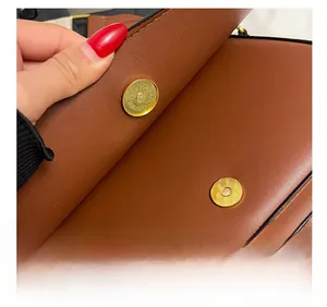 Détail d'un sac besace en cuir marron avec un fermoir magnétique doré de haute qualité