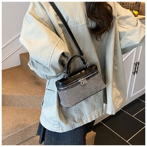 Detail shot of a contrast stitching square bag with herringbone pattern and silver lock