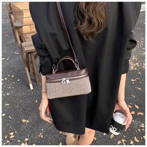 Close-up of contrast stitching herringbone crossbody bag with brown leather details