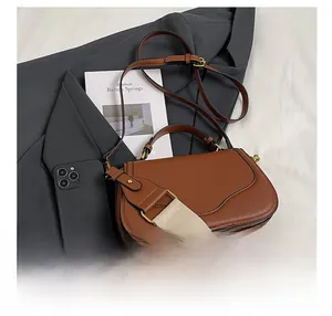 Sacoche marron en cuir avec deux bandoulières à côté d'un smartphone pour comparer la taille
