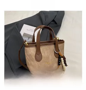Close-up of retro brown canvas bag with leather trim and decorative bead pendant
