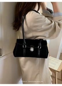 Close-up of black suede retro baguette bag with silver twist lock on a beige trench coat